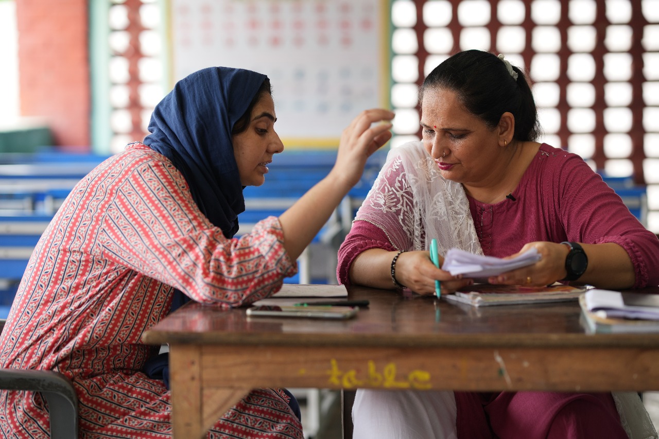 Two education officials reviewing learning materials together at a school in India